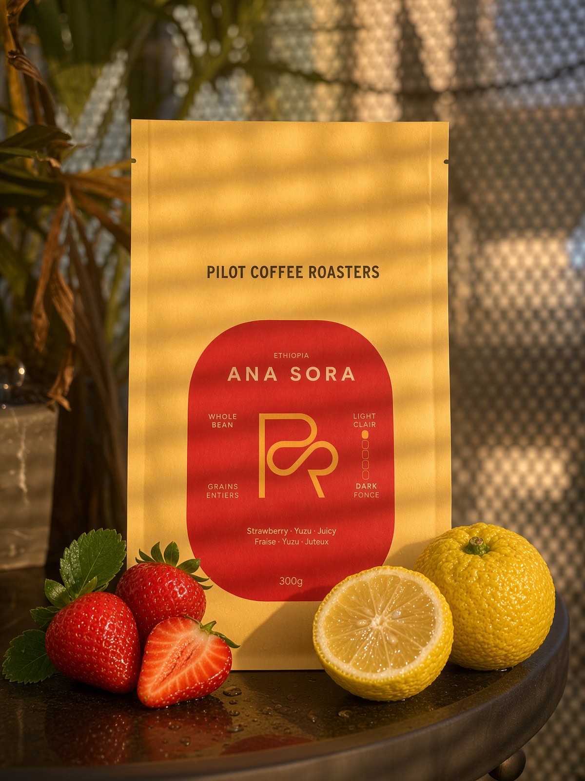 The Ana Sora bag from Pilot Coffee Roasters, beside strawberries and a lemon.